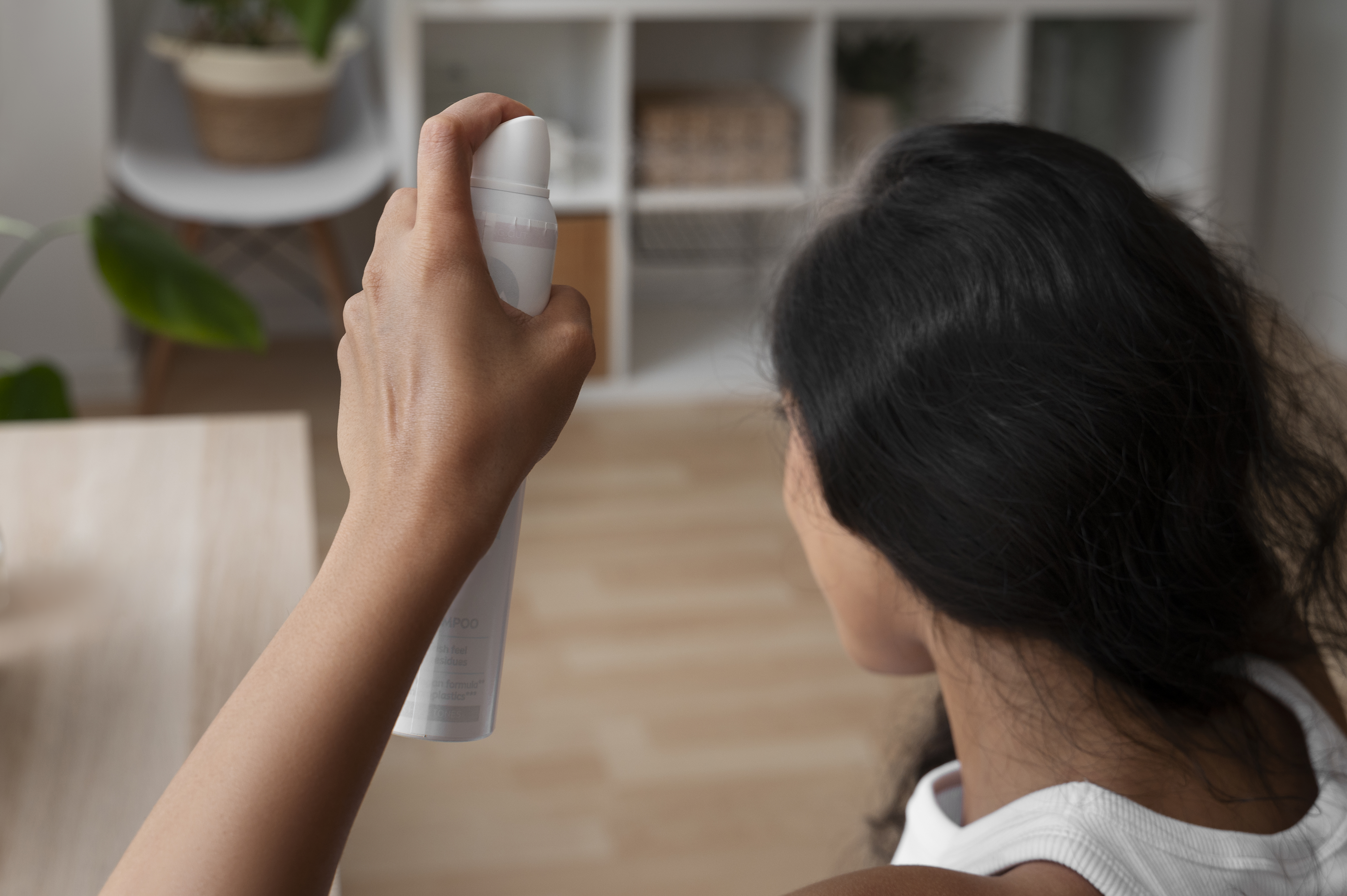 Woman spraying her scalp with dry shampoo