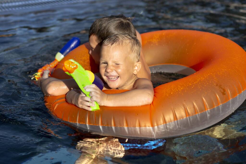Kids playing in a pool with a water gun