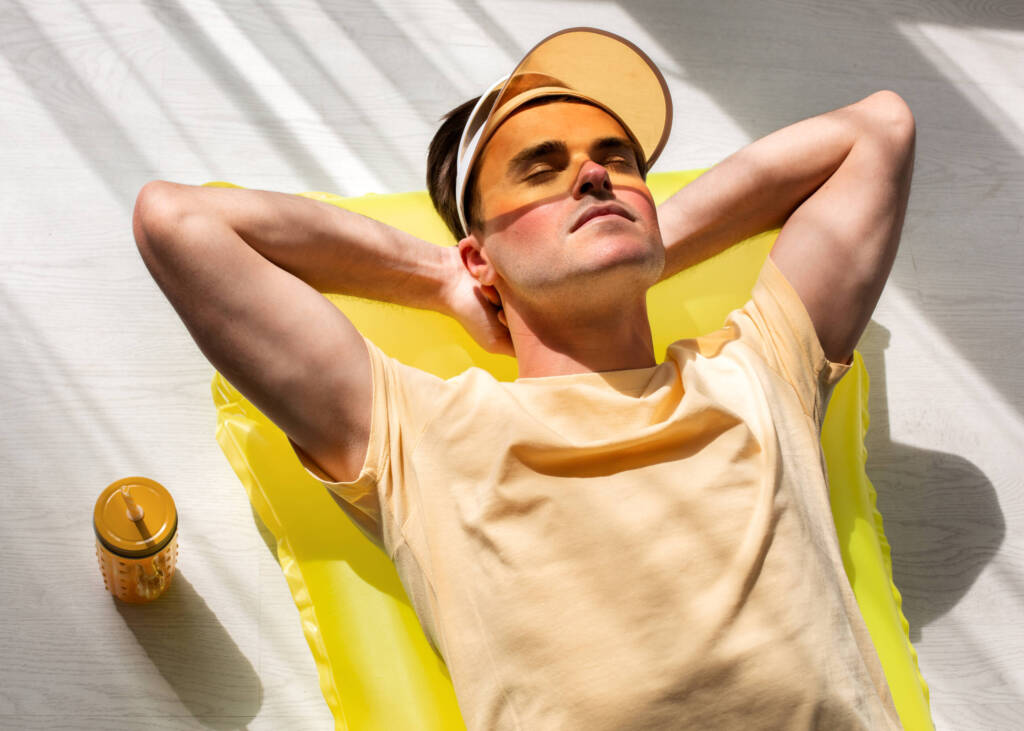 Man sitting in striated sunlight with visor