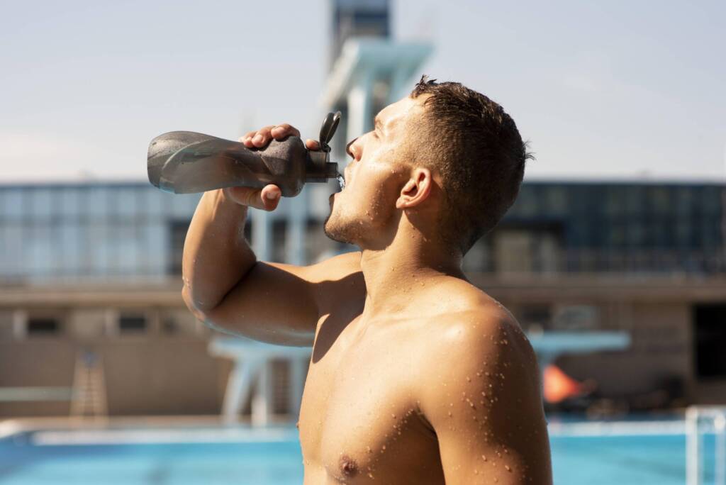 Man drinking water poolside