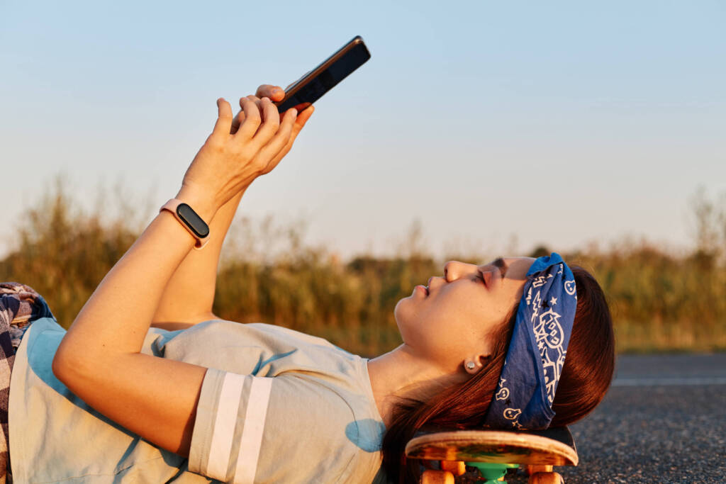 Teenager checking cell phone on a skateboard