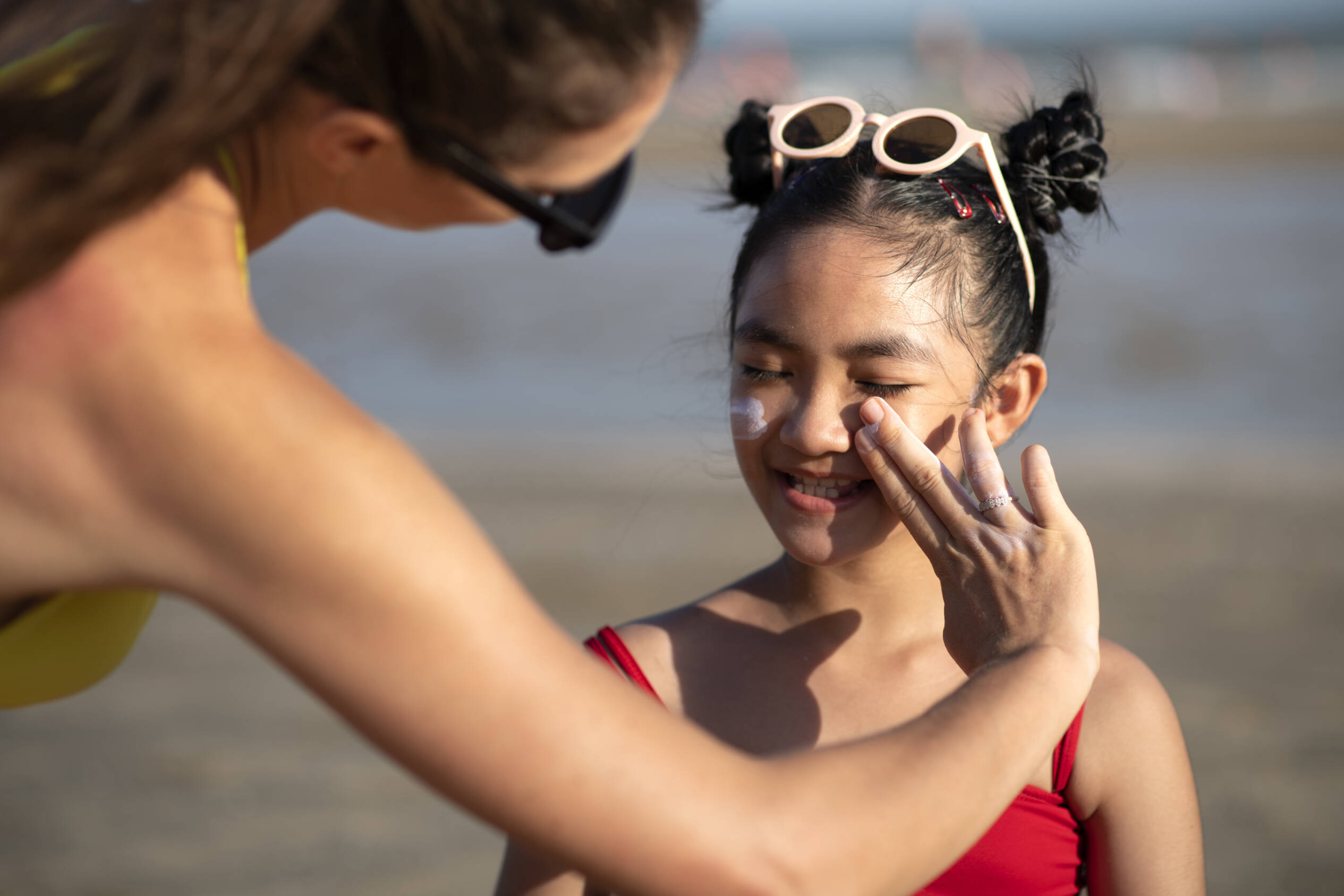 Parent spreading sunscreen on child