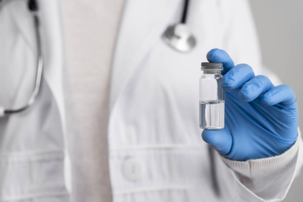 Doctor holding a vial of clear liquid