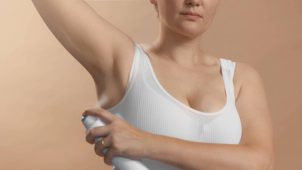 Woman spraying on deodorant