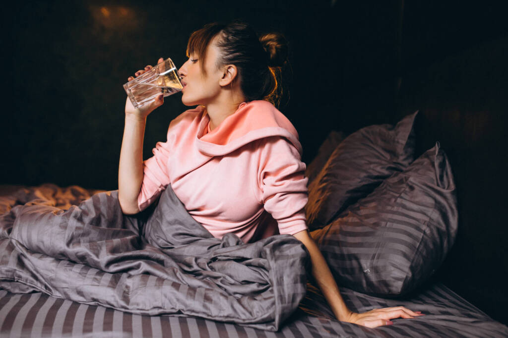 Woman in bed sipping water