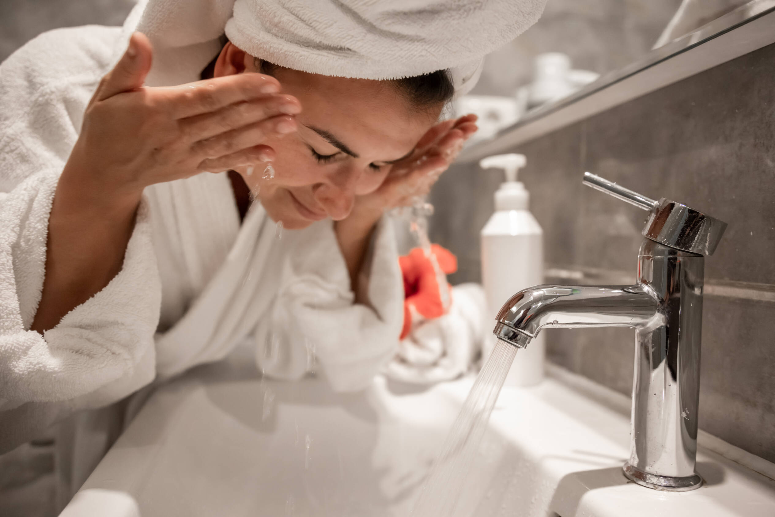 Woman splashing face with tap water