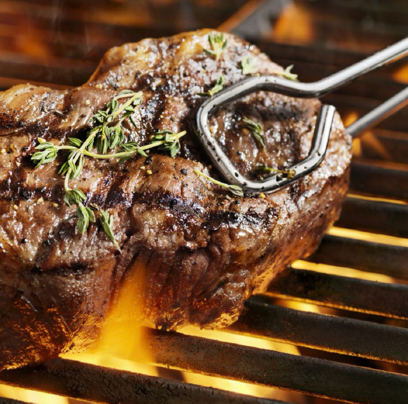 Grill master turning over a Kangen wagyu steak on the grill